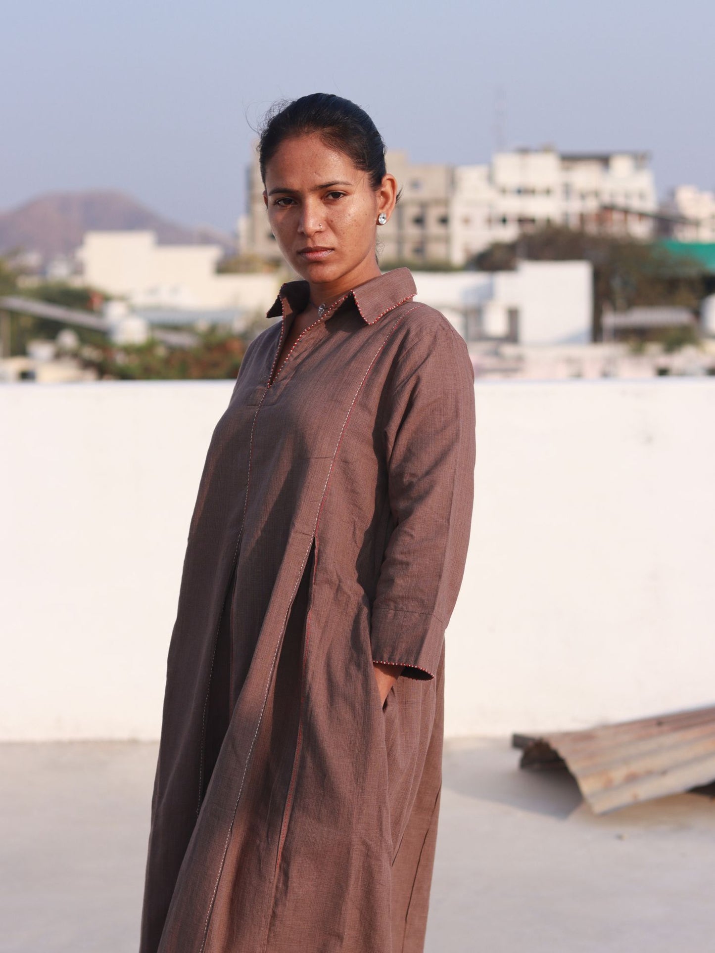 Side view of a woman wearing an earthy brown box pleat cotton Indo-Western dress with a shirt collar.