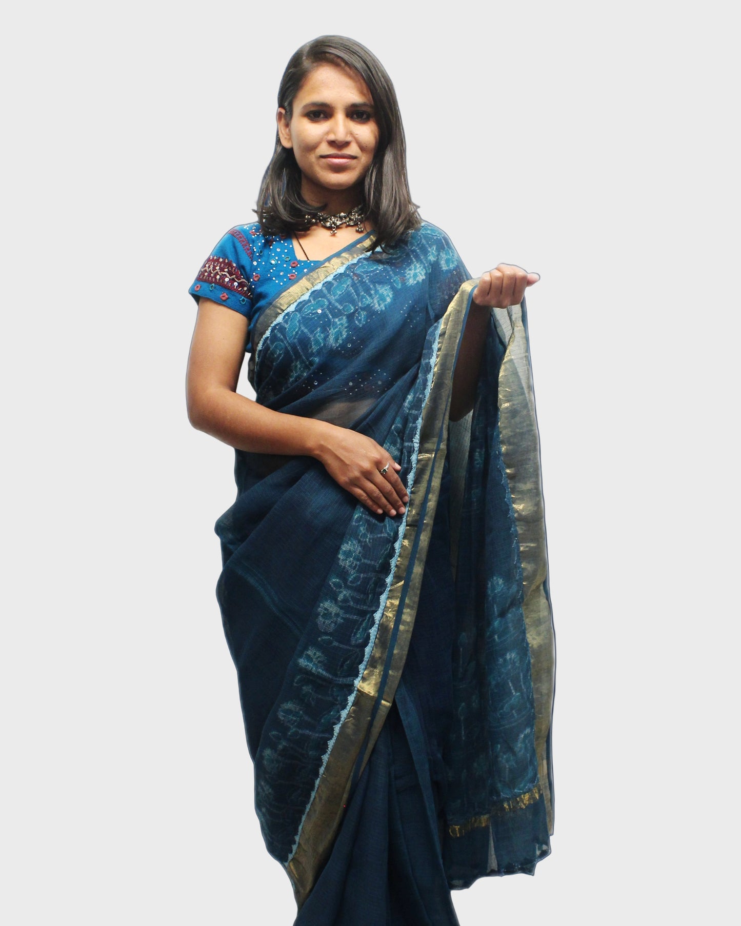 A woman showcasing a turquoise Kota Doriya silk saree with zari and applique border.
