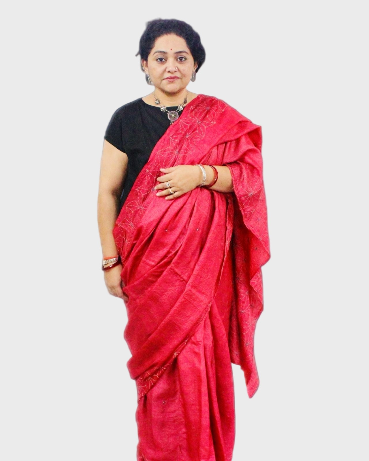 Woman wearing a red saree with a black blouse on a gray background