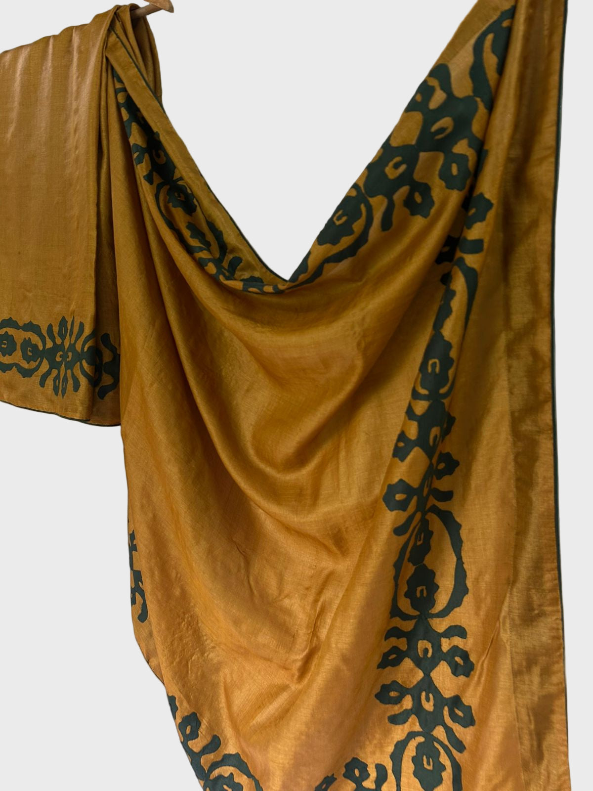 Mustard yellow fabric with black floral patterns draped over a white surface