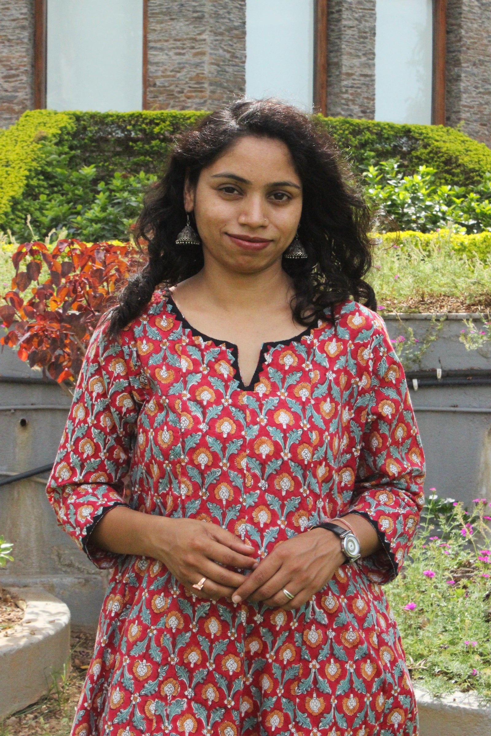 Woman wearing handcrafted red floral A-line cotton dress with block print and three-quarter sleeves outdoors.