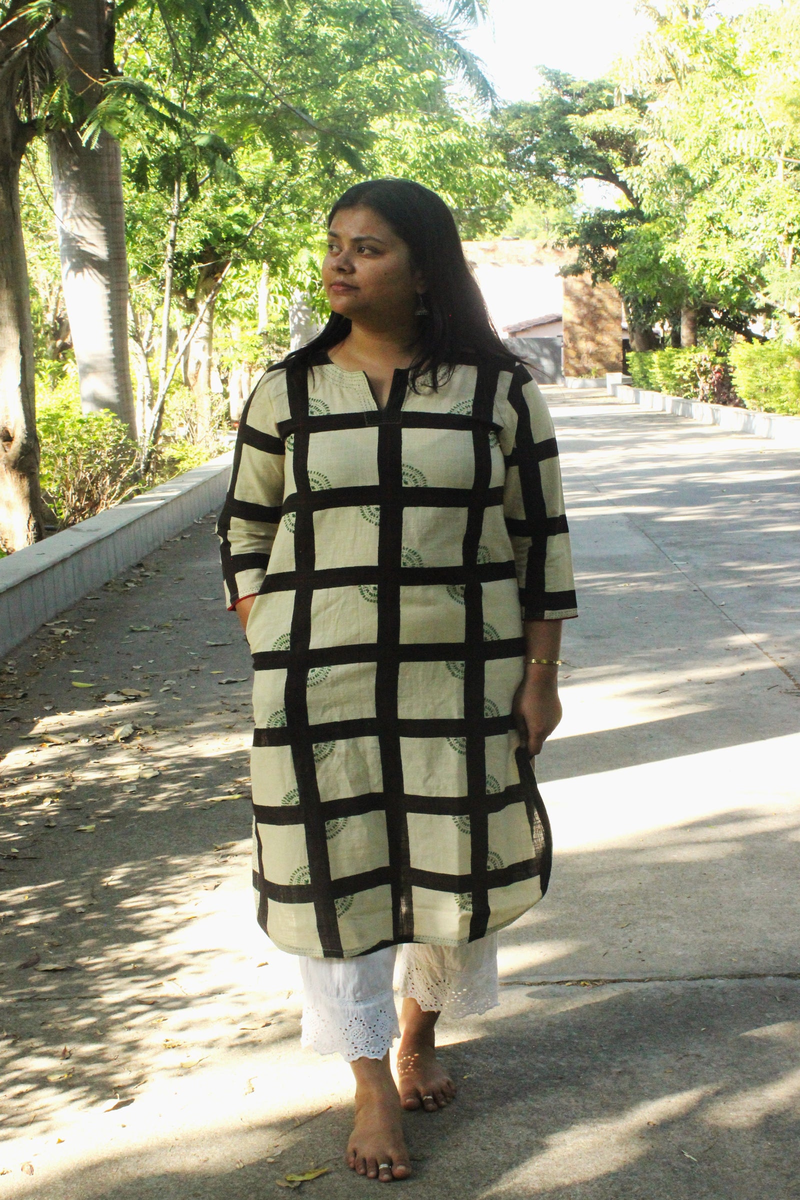 Woman wearing handcrafted off-white straight cotton kurta with checkered print and hand embroidery.