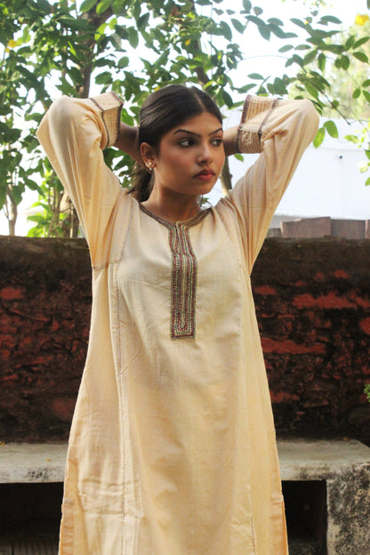 Woman wearing handcrafted striped beige cotton A-line kurta with hand embroidery and three-quarter sleeves.
