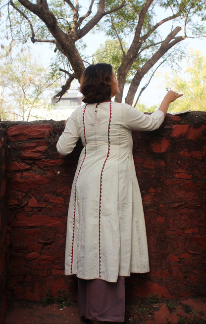 Front view of a white handcrafted appliqué cotton A-line kurta with side pockets on a model.