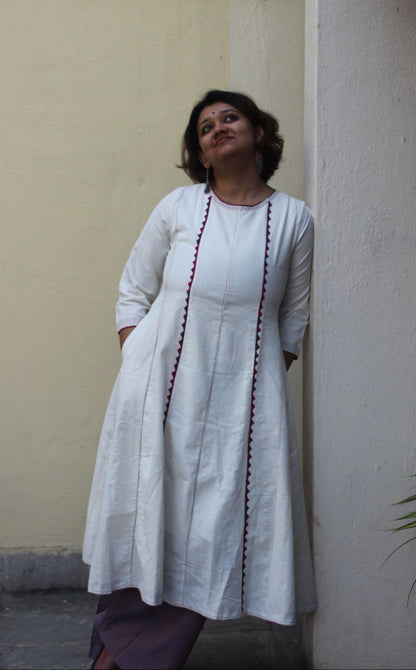 Front view of a white handcrafted appliqué cotton A-line kurta with side pockets on a model.