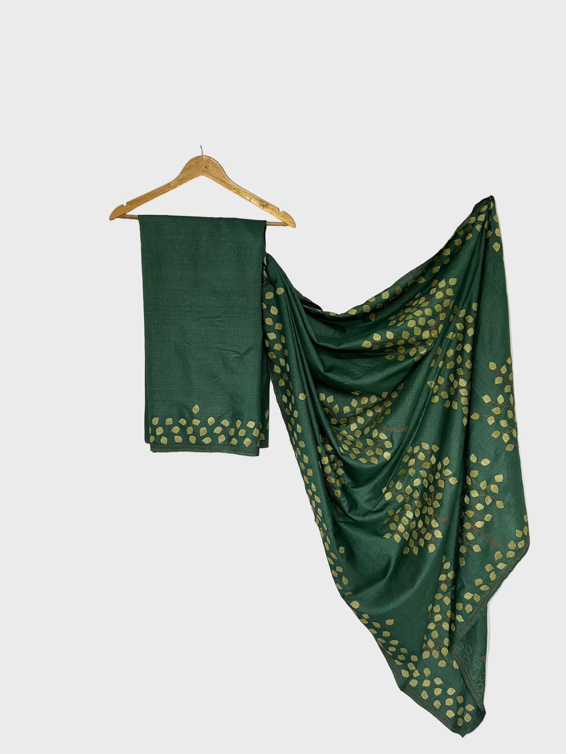 Green saree with gold patterns draped over a white backdrop