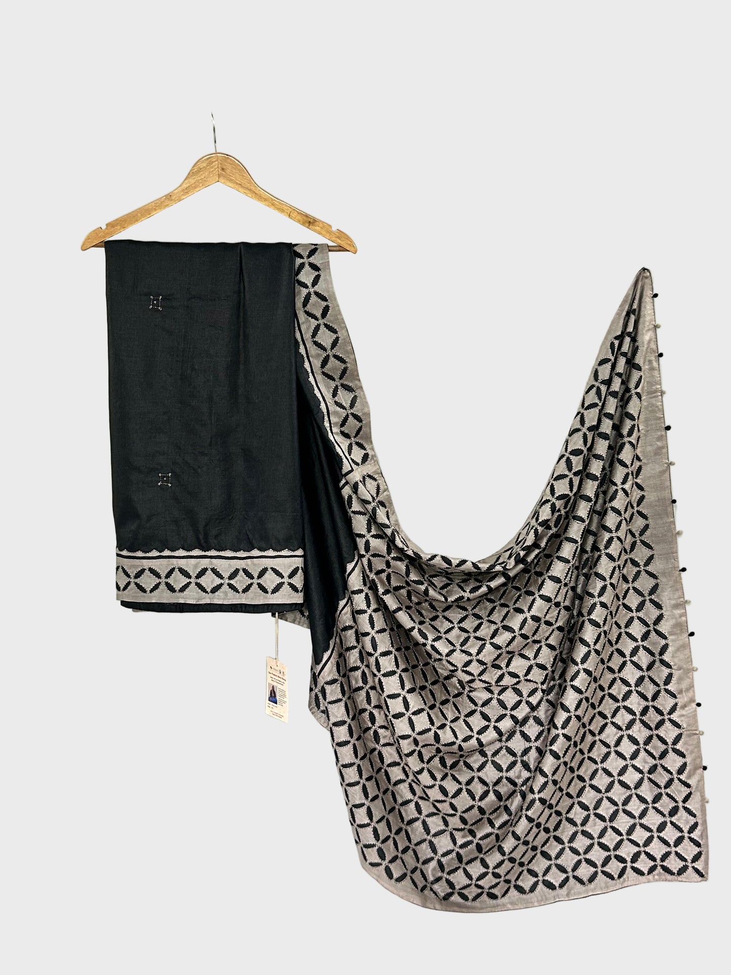 Black and patterned scarf draped over a white surface with a hanger.