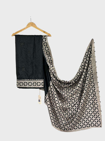 Black and patterned scarf draped over a white surface with a hanger.