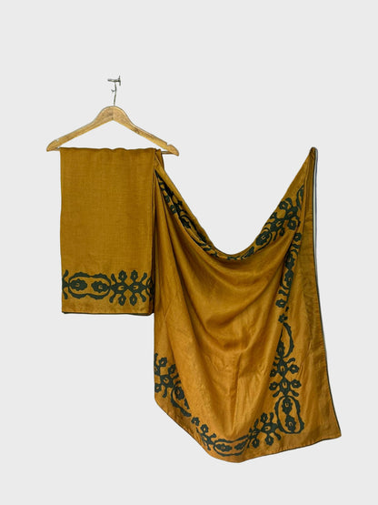 Mustard yellow fabric with black embroidery on a white background